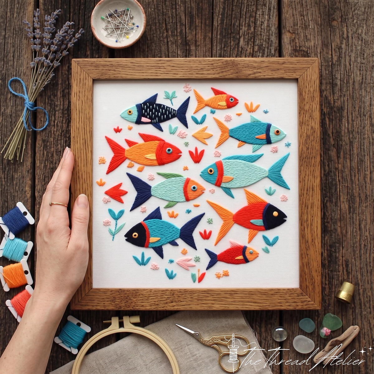 School of fish needlework arranged in a rustic square frame with floss and gold scissors